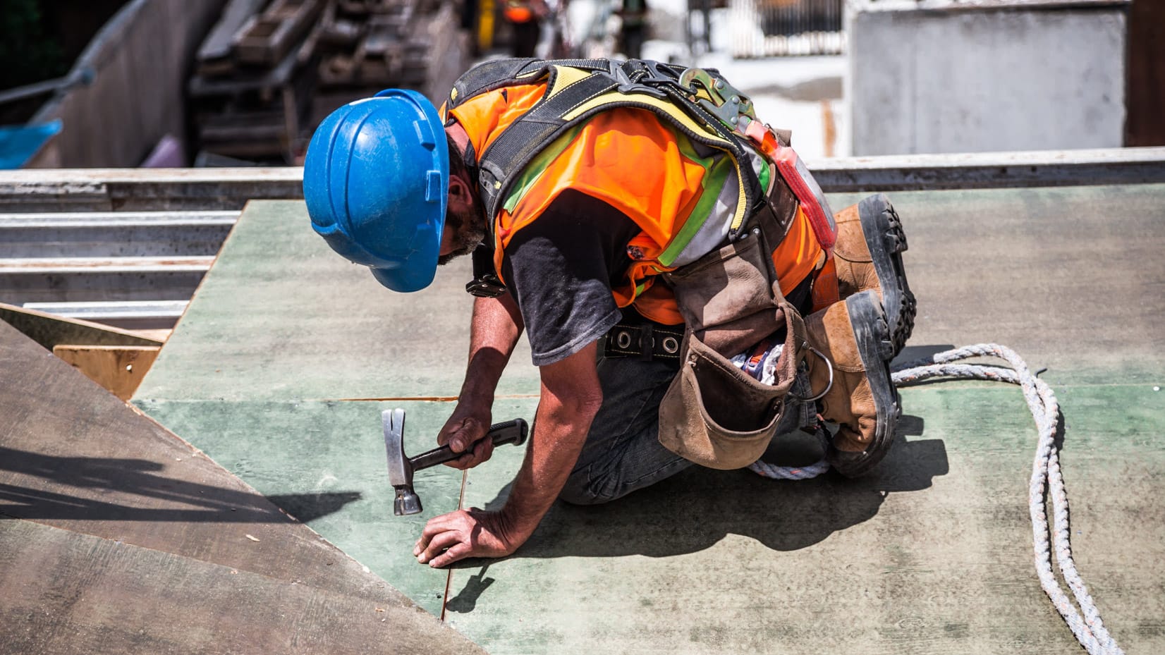 Construction worker hammering on top of a building