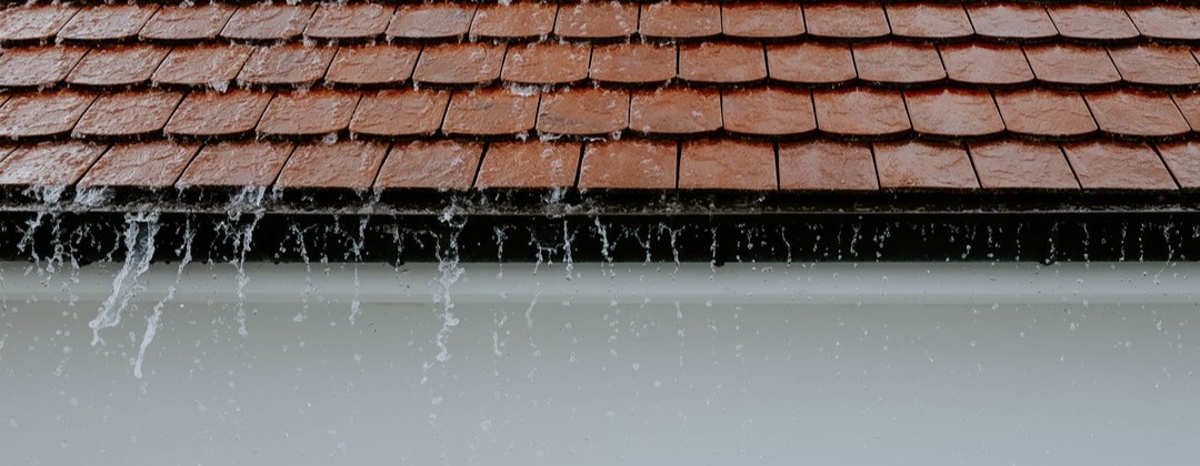 Signs of Waterproofing Failure in Commercial Buildings - Rain cascading down roof