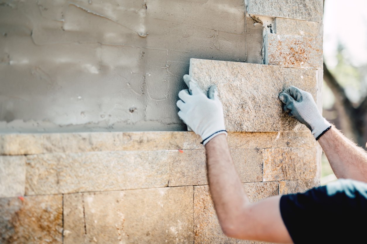 mason placing stone on building, masonry facade, building restoration products